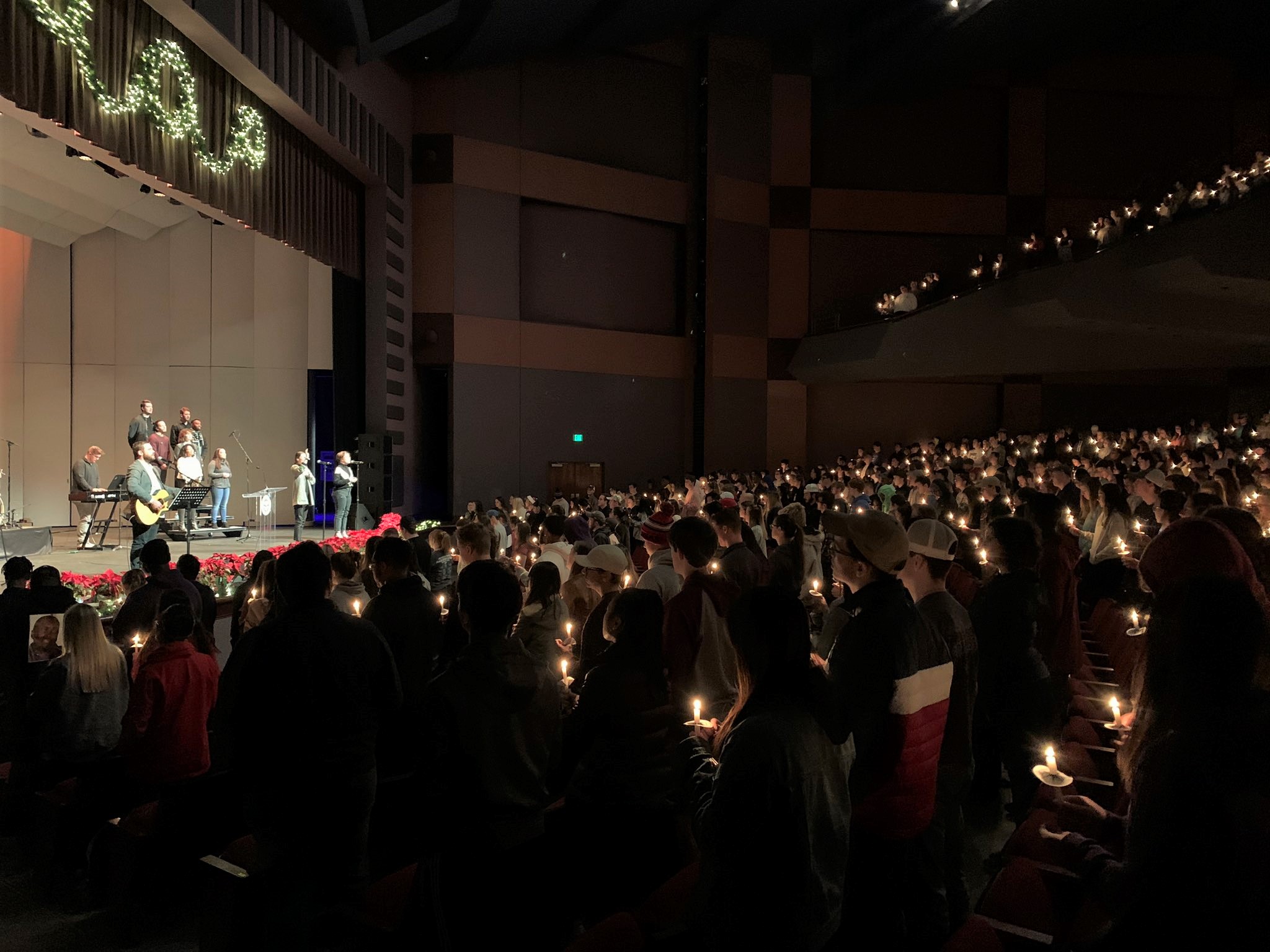 Students light candles during Chapel at Christmas time 